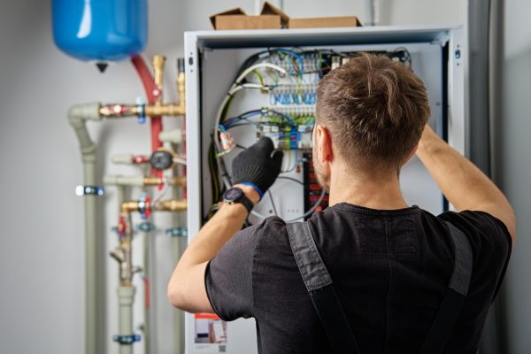 Electrician Repairing Heat Pump Control Panel Electrician Repairing Heat Pump Control Panel