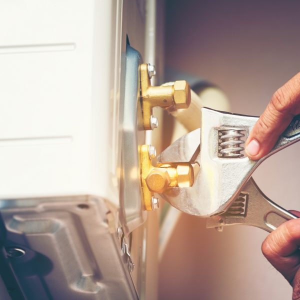 Technician hand using fix wrench to tighten outdoor unit of air condition Technician hand using fix wrench to tighten outdoor unit of air condition