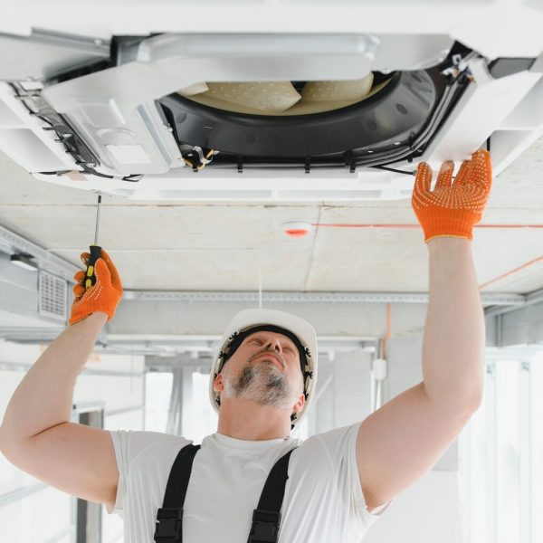 Worker repairing ceiling air conditioning unit Worker repairing ceiling air conditioning unit